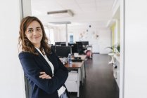 Впевнена в собі бізнесжінка стоїть і посміхається в офісі — стокове фото