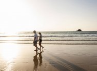 Молода пара робить романтичну прогулянку пляж на захід сонця — стокове фото