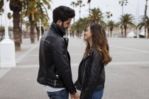 Smiling romantic young couple on promenade with palms — Stock Photo