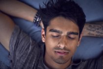 Молода людина з татуюванням, відпочиваючи на подушці, уві сні — стокове фото