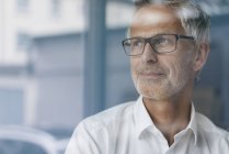 Erfolgreicher Manager blickt aus dem Fenster, denkt nach, porträtiert — Stockfoto