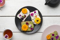 Toast con hummus di avocado e formaggio sprad con fiori commestibili — Foto stock