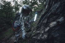 Spaceman esplorare la natura, utilizzando torcia nella foresta oscura — Foto stock