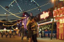 Feliz jovem casal abraçando e beijando em uma feira — Fotografia de Stock