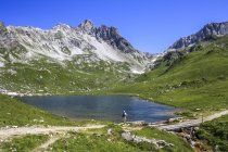 Austria, Vorarlberg, Hiker standing at mountain lake — Stock Photo
