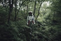 Spaceman exploring nature, walking in green forest — Stock Photo