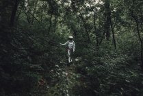 Spaceman exploring nature, looking at plants in forest — Stock Photo