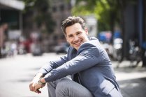 Retrato del hombre feliz sentado en la ciudad - foto de stock