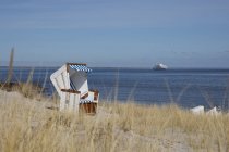 Німеччина, Шлезвіг-Гольштейн, Зільт, список, порожній пляж з капюшоном стілець, круїзне судно у фоновому режимі — стокове фото
