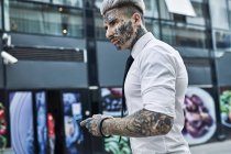 Jeune homme d'affaires au visage tatoué avec smartphone — Photo de stock