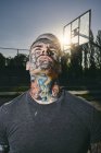 Portrait of tattooed young man on basketball court — Stock Photo
