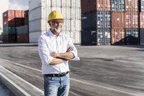 Homme d'affaires au port de fret, casque de sécurité, bras croisés — Photo de stock
