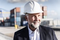 Businessman at cargo harbour, wearing safety helmet, portrait — Stock Photo