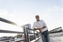 Uomo maturo in piedi sul tetto di un grattacielo, appoggiato alla ringhiera — Foto stock