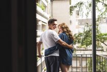 Casal feliz em roupa de noite de pé na varanda abraçando — Fotografia de Stock