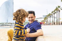 Spanien, Barcelona, kleiner Junge spielt mit Sand, sein Vater sitzt neben ihm und lächelt — Stockfoto