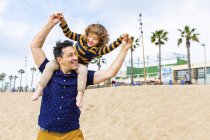 Espanha, Barcelona, pai com filho na praia dando um passeio de piggyback — Fotografia de Stock