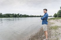 Homme debout au bord de la rivière regardant dehors — Photo de stock