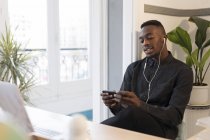 Ritratto di giovane uomo d'affari con smartphone e auricolari in ufficio — Foto stock