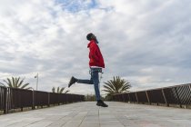 Молодой чернокожий стоит на улице, прыгает от радости — стоковое фото