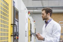 Contrôle des employés des machines de fabrication dans l'entreprise de haute technologie, en utilisant une tablette numérique — Photo de stock