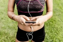 Девушка-подросток, использующая смартфон и наушники на гоночной трассе — стоковое фото