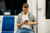 Молодий чоловік користується смартфоном у метро. — стокове фото