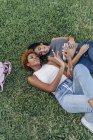 Zwei Freundinnen entspannen sich in einem Park und hören Musik — Stockfoto