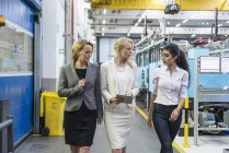 Trois femmes avec tablette marche et parler dans l'atelier de l'usine — Photo de stock