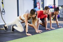 Young people exercising plank variations in a gym — Stock Photo