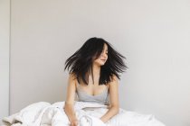 Mujer joven en la cama agitando la cabeza - foto de stock