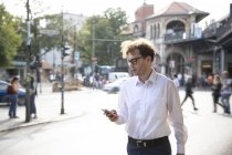 Alemanha, Berlim, homem de negócios olhando para o telefone celular ao ar livre — Fotografia de Stock