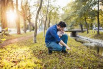 Vater auf Kastaniensuche im Park, kleine Tochter auf dem Schoß — Stockfoto
