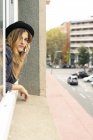 Молода жінка витріщається з вікна, розмовляючи на мобільний телефон — стокове фото