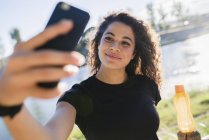 Sportliche junge Frau macht ein Selfie am Flussufer — Stockfoto