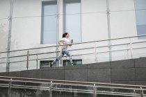 Giovane donna che corre lungo edificio in città — Foto stock