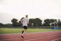 Athlete running on tartan track — Stock Photo