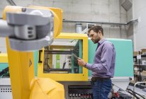 Empresario verificando robot industrial en compañía de alta tecnología - foto de stock