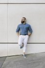 Homem de negócios hipster barbudo usando óculos e camisa xadrez, encostado à parede — Fotografia de Stock