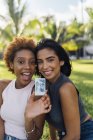 Two happy female friends showing an instant photo in a park — Stock Photo