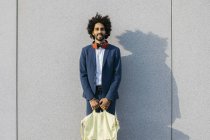 Ritratto di giovane uomo d'affari sorridente con borsa e cuffie a muro — Foto stock