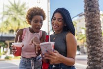 États-Unis, Floride, Miami Beach, deux amies heureuses avec téléphone portable et boisson gazeuse dans la ville — Photo de stock
