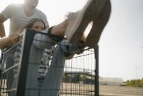 Carefree giovane uomo spingendo fidanzata in un carrello della spesa — Foto stock