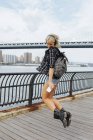 Usa, new york city, brooklyn, glückliche junge frau mit kopfhörer und handy springen am ufer — Stockfoto