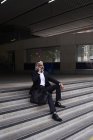 Homem de negócios sênior elegante falando por smartphone enquanto sentado em escadas ao ar livre — Fotografia de Stock