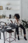 Mujer que trabaja en su oficina en casa, usando un teléfono inteligente - foto de stock