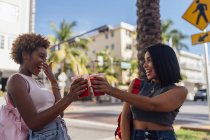 USA, Florida, Miami Beach, dos amigas felices tomando un refresco en la ciudad - foto de stock