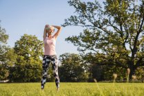 Senior woman stretching on rural meadow — Stock Photo