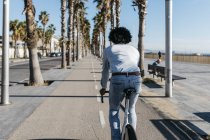 African american man riding bicycle in the city, near the beach — Stock Photo