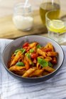 Penne with tomato and basil leaves in bowl on table — Stock Photo